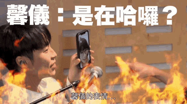 a man is holding a cell phone in front of a microphone with flames in the background