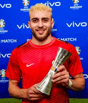 a man in a red shirt is holding a trophy in front of a blue background that says vivo