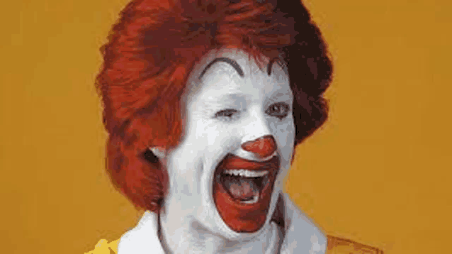 a close up of a mcdonald 's clown with red hair and white face paint .