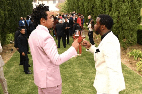 two men in suits are toasting with wine glasses outside