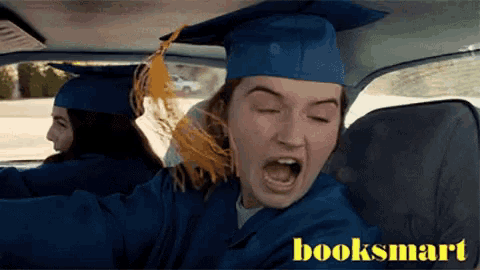 a woman in a graduation cap and gown is driving a car with booksmart written on the bottom