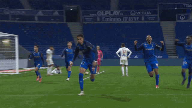 a group of soccer players are running on a field with an advertisement for emirates fly better in the background