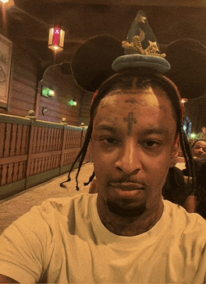 a man with a cross on his forehead wears a mickey mouse hat