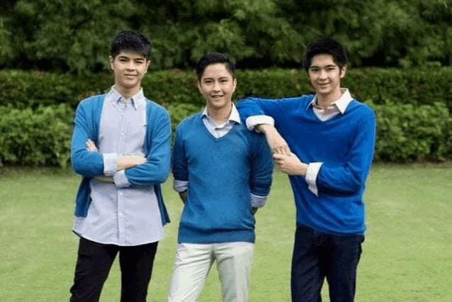 three young men are standing next to each other in a field .