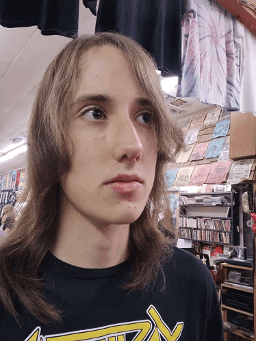 a young man with long hair is wearing a black shirt with a yellow arrow on it