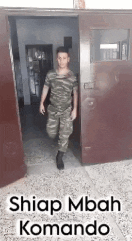 a man in a military uniform is walking through a doorway .