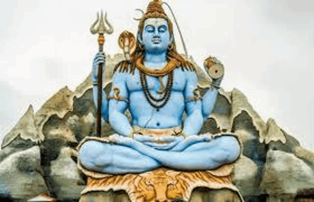 a statue of lord shiva is sitting on top of a rock holding a trident .