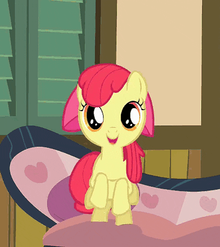 a cartoon pony with a pink mane and tail is sitting on a bed