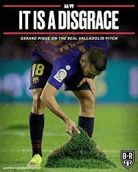 a soccer player is kneeling down on a soccer field and looking at a pile of grass .