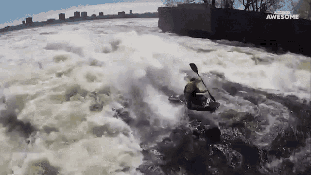 a man in a yellow jacket is paddling a kayak in a river and the words awesome are on the bottom