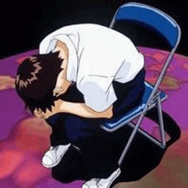 a man is sitting on a chair with his head on his knees .