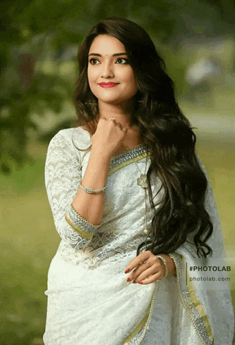 a woman wearing a white lace blouse with a gold border is standing in a field