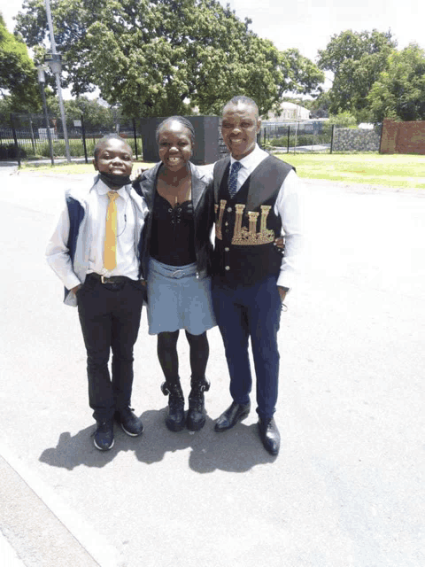 a man wearing a vest that says ' lil ' on it poses with two other people