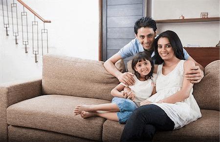 a family is sitting on a couch in a living room smiling for the camera .