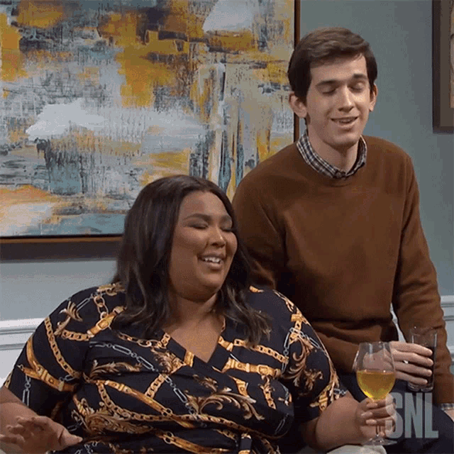 a man and a woman are sitting on a couch with snl written on the bottom of the screen