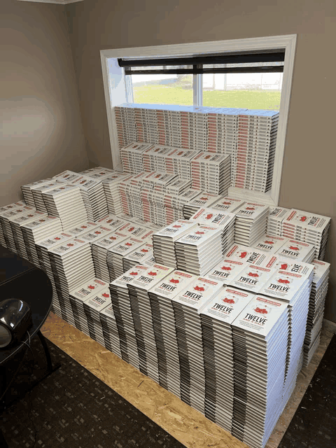 a large stack of twelve books sits on a table