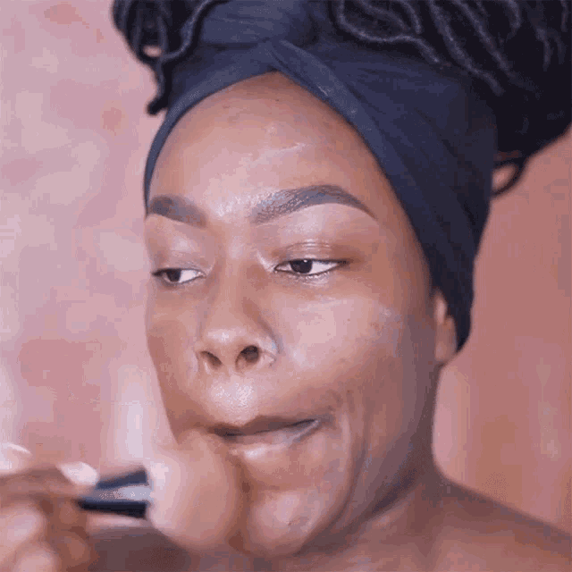 a woman is applying makeup to her face with a brush