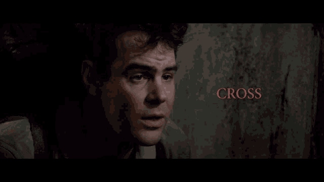 a man in a dark room with the words cross the streams in red