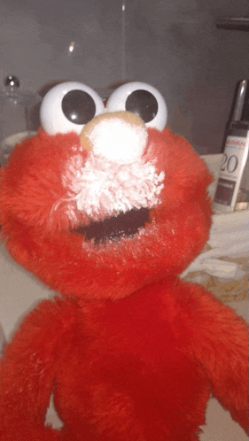 elmo stuffed animal with powder on his face in front of a salt shaker with the number 20 on it