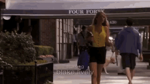 a woman in a yellow top is walking down a sidewalk in front of a building that says four forty