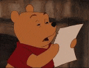 winnie the pooh is reading a piece of paper and making a funny face .