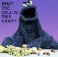 a stuffed cookie monster is sitting on a table with grapes and bones .