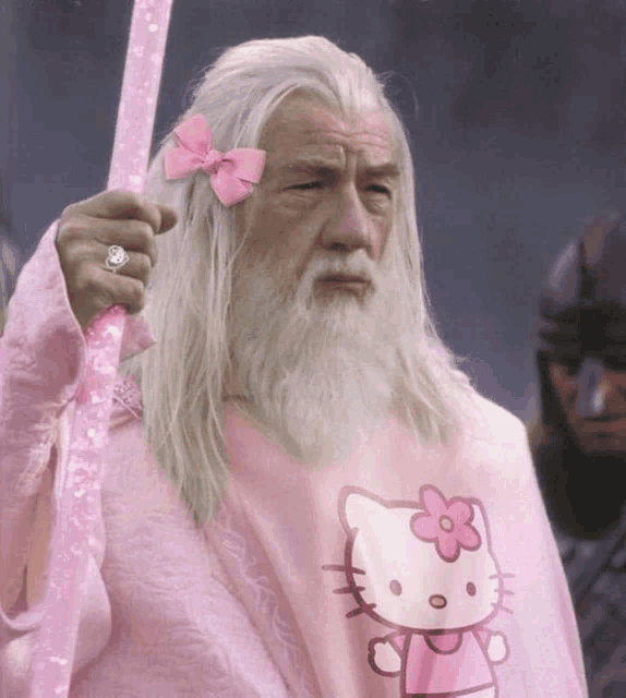 a man with a beard is wearing a pink hello kitty shirt and has a pink bow in his hair