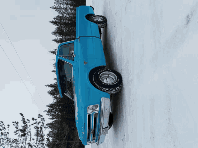 a blue truck is parked in the snow with eagle st tires on it