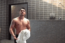 a shirtless man is holding a white towel in a bathroom .