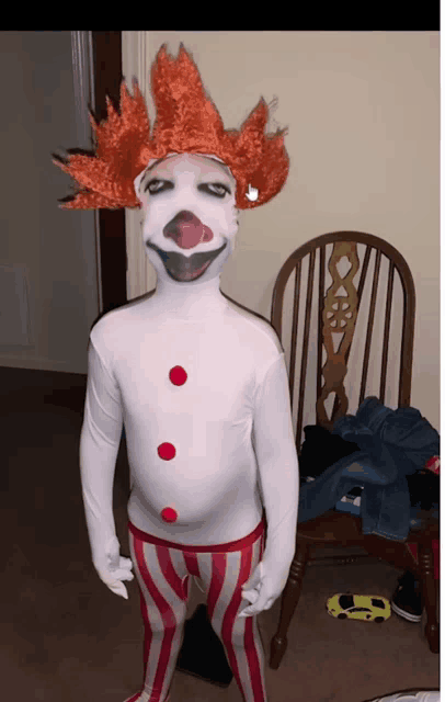 a child dressed in a clown costume stands in front of a chair