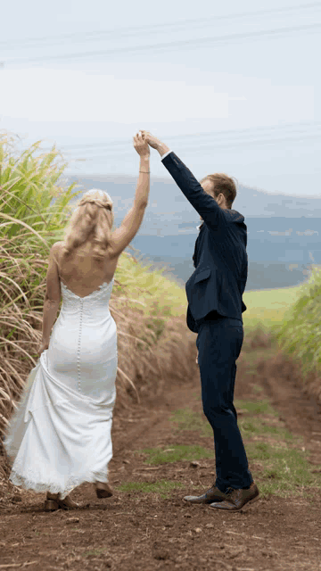 a bride and groom are holding hands in a field