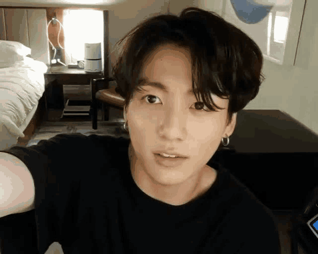 a young man is taking a selfie in a hotel room while wearing a black shirt .