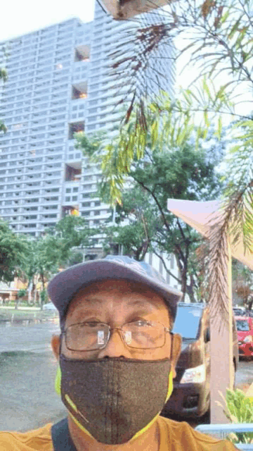 a man wearing a mask and glasses is taking a selfie in front of a tall building