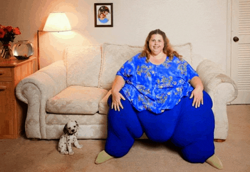 a woman sits on a couch with a dalmatian dog