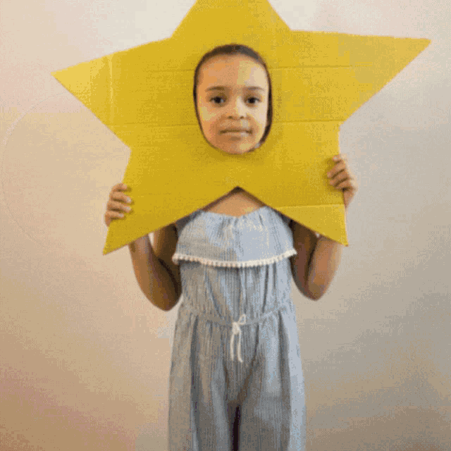 a little girl is holding a cardboard star in front of her face and says may this day bring cheer