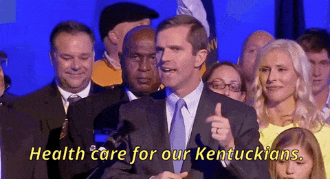 a man in a suit and tie is giving a thumbs up in front of a crowd of people .