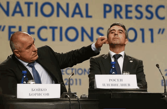 two men are sitting at a table with a sign that says " bojko boricov "