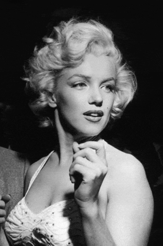 a black and white photo of marilyn monroe holding her hand to her face