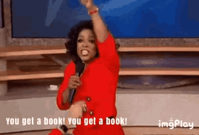 a woman in a red dress is holding a microphone and saying " you get a book "