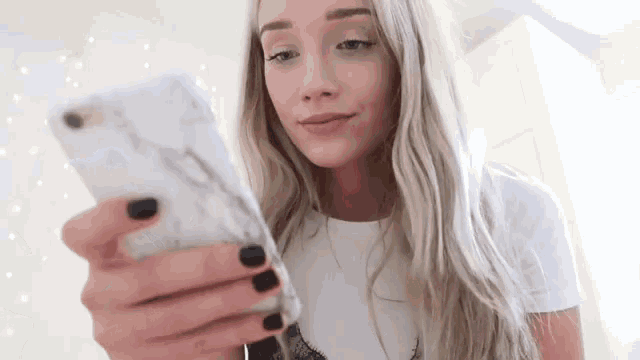 a woman with long blonde hair is looking at her phone