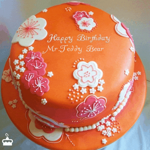 an orange birthday cake with pink and white flowers and the words happy birthday mr. teddy bear