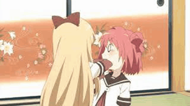 two anime girls are standing next to each other in a room . one of the girls is petting the other 's head .