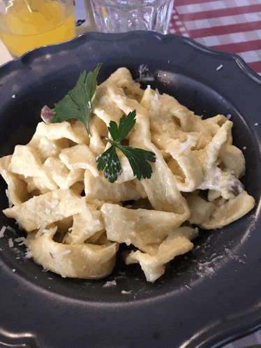 a black plate topped with pasta and parsley on a table