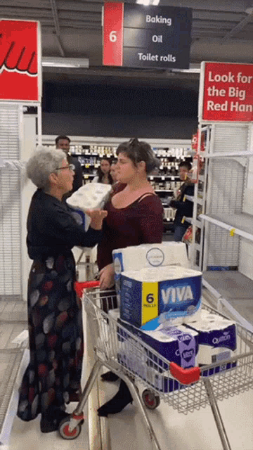 a woman pushing a shopping cart full of toilet rolls in front of a sign that says baking oil and toilet rolls