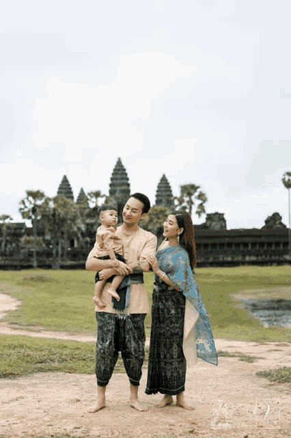 a man and woman holding a baby in front of a building