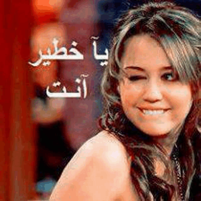 a woman is smiling and winking at the camera with arabic writing on her face .