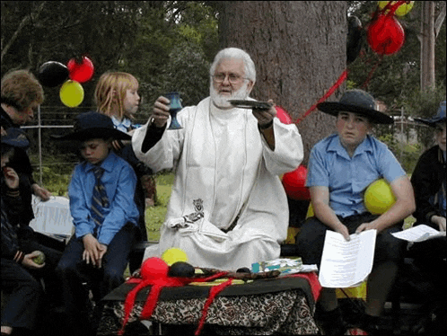 a man in a white robe is holding a chalice in front of a group of kids