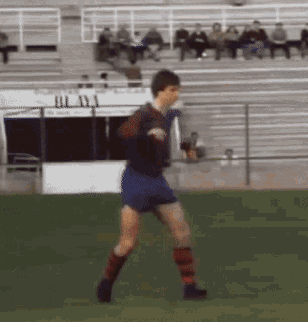 a soccer player is running on a field with a stadium in the background and a sign that says ' ul ' on it