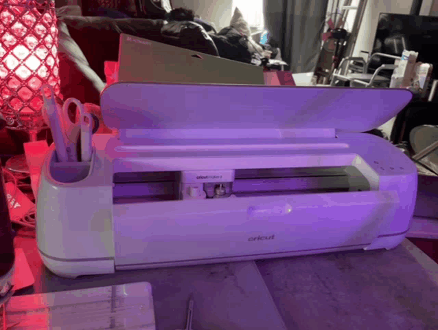 a cricut machine sits on a table with purple lights behind it