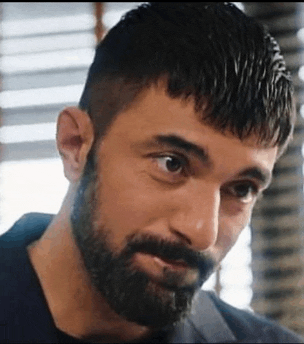 a close up of a man with a beard and a fringe looking at the camera .